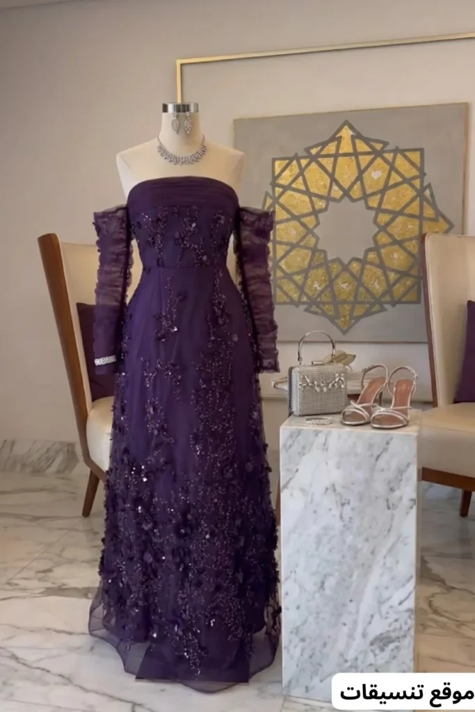 صورة تنسيق فستان سهرة طويل باللون البنفسجي الداكن بتطريزات وزهور بارزة وأكمام شيفون منفصلة، طقم مجوهرات فضي، حقيبة يد فضية صغيرة مربعة، وحذاء فضي بكعب.