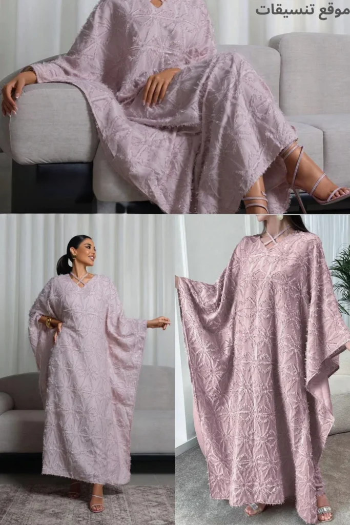 صورة مودل ترتدي جلابية رمضانية باللون الوردي البودرة، قماش منسوج بتفاصيل بارزة (شراشيب ناعمة)، قصة واسعة وياقة على شكل V، مع حذاء كعب عالي بسيور.