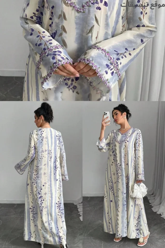 جلابية رمضان باللون الأبيض مع طبعات زهور زرقاء عامودية، أكمام طويلة مزينة بتطريز بنفسجي عند الأطراف والياقة، موديل صيفي ناعم.