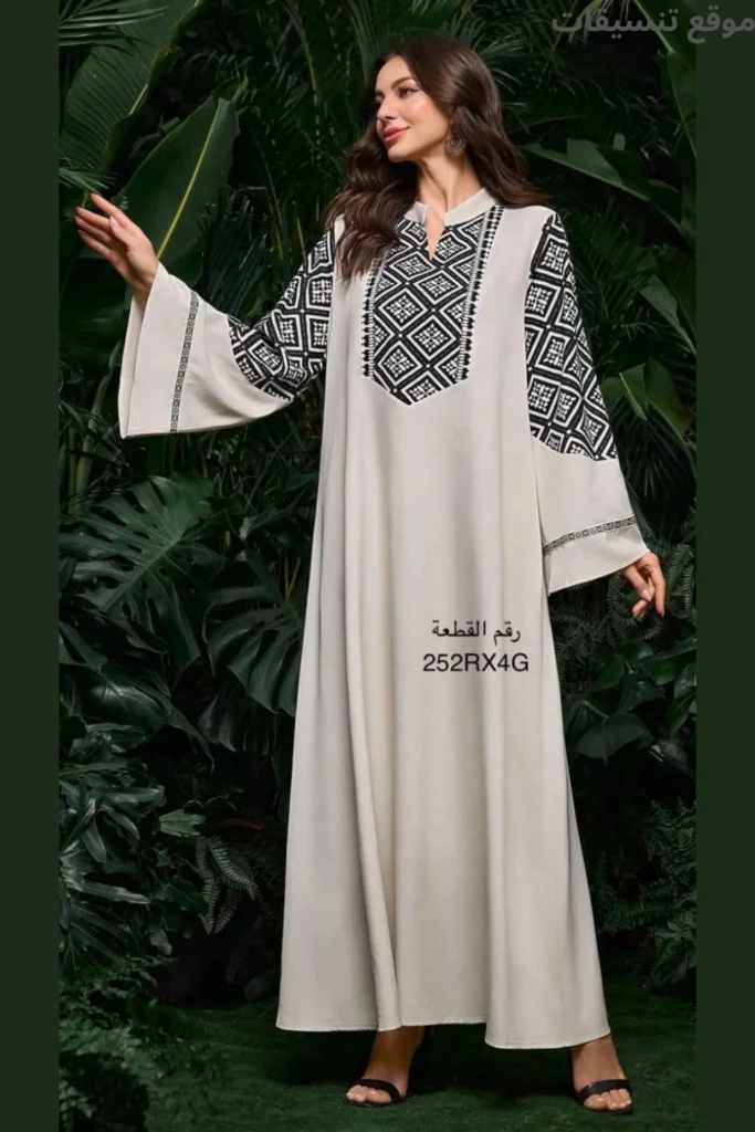 جلابية باللون الأوف وايت، تتميز بتطريز هندسي بارز باللون الأسود يغطي منطقة الصدر والأكتاف العريضة، قصة منسدلة.