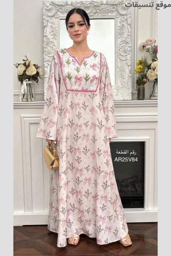 جلابية باللون الوردي الفاتح مغطاة بالكامل بطبعات فيونكات وزهور صغيرة، صدرية مربعة مطرزة بالورود، ستايل بناتي ناعم.
