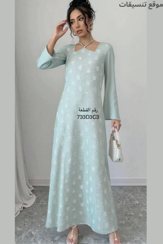 جلابية باللون التيفاني (أخضر مائي) فاتح، قماش بارز الملمس (تيكستشر) بنقوش ناعمة، ياقة بتصميم مميز مع أشرطة متقاطعة حول الرقبة.