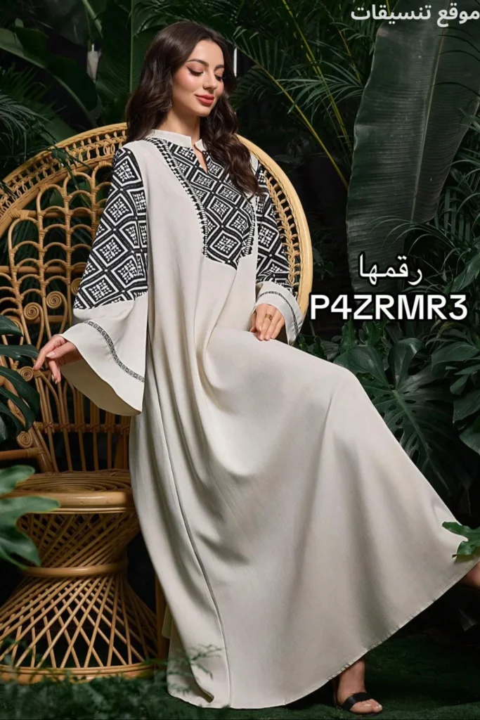 جلابية باللون الأوف وايت (السكري)، تتميز بتطريز هندسي أسود كثيف وعريض يغطي الأكتاف والصدر وجزء من الأكمام، قصة واسعة جداً.