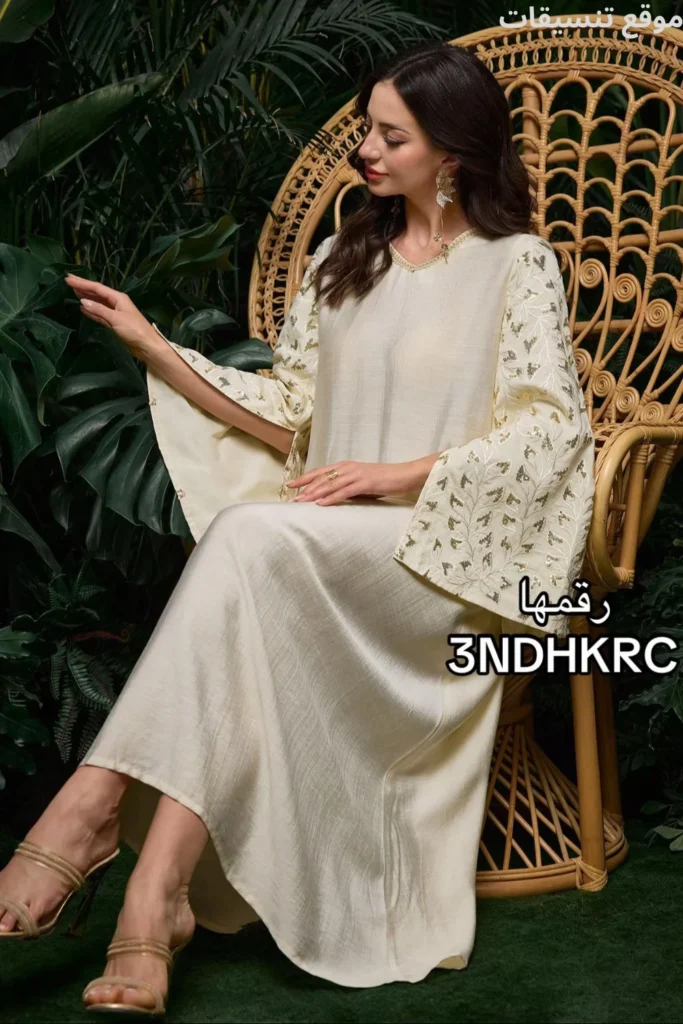 جلابية من قماش ساتان لامع بلون ذهبي باهت (شامبين)، أكمام واسعة جداً (كيمونو) مزينة بتطريز أوراق شجر ذهبية، قصة انسيابية.