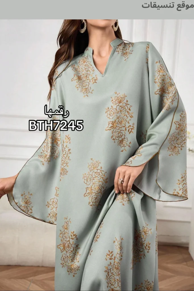 جلابية باللون الأخضر الزيتي الفاتح (Sage Green)، مطبوعة بزهور ذهبية/بنية دقيقة، ياقة صغيرة (V-neck)، وأكمام واسعة ومريحة.