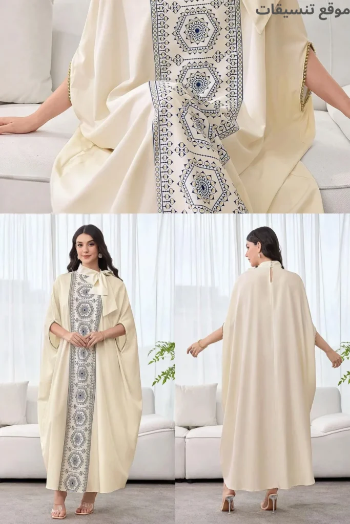 جلابية بلون بيج كريمي، شريط تطريز عريض بنقوش هندسية زرقاء يمتد من الرقبة للأسفل، ياقة عالية مع ربطة جانبية (فيونكة).